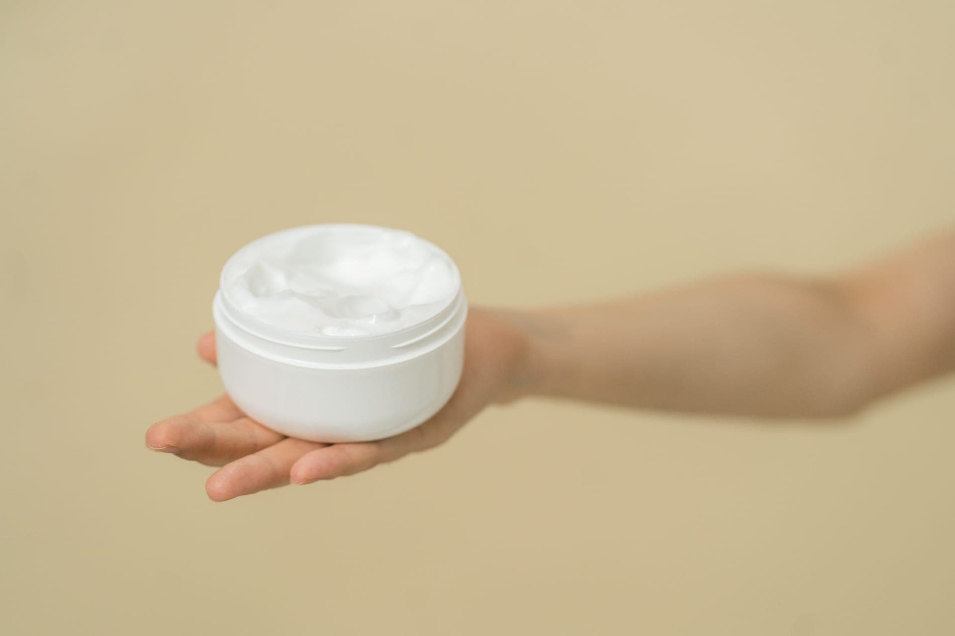 A swatch of cream beside an open jar on a warm neutral surface