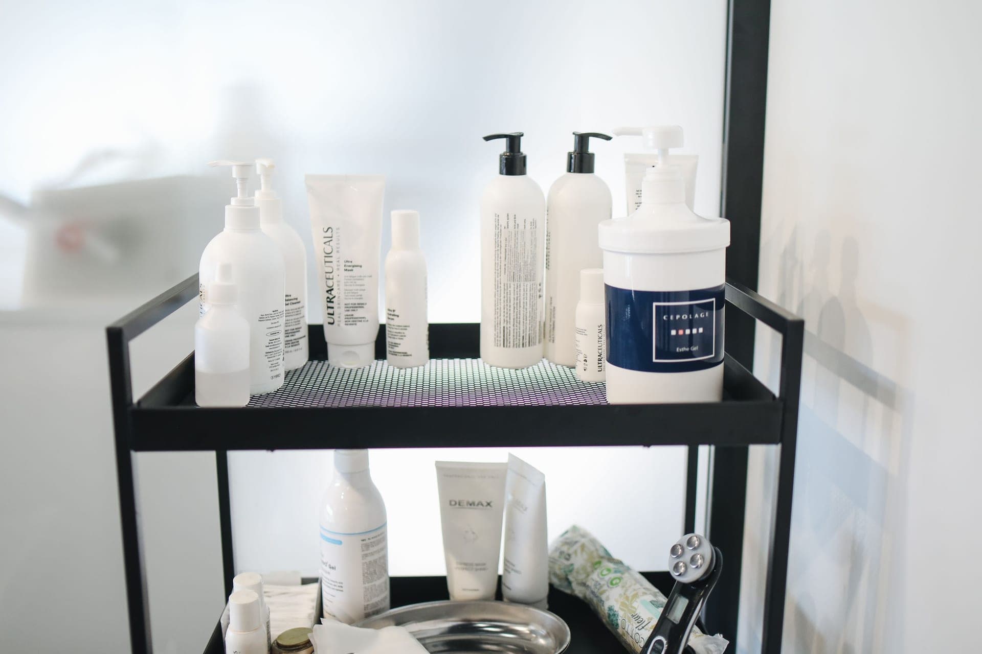 A small shelf of unbranded skincare bottles in warm lamplight